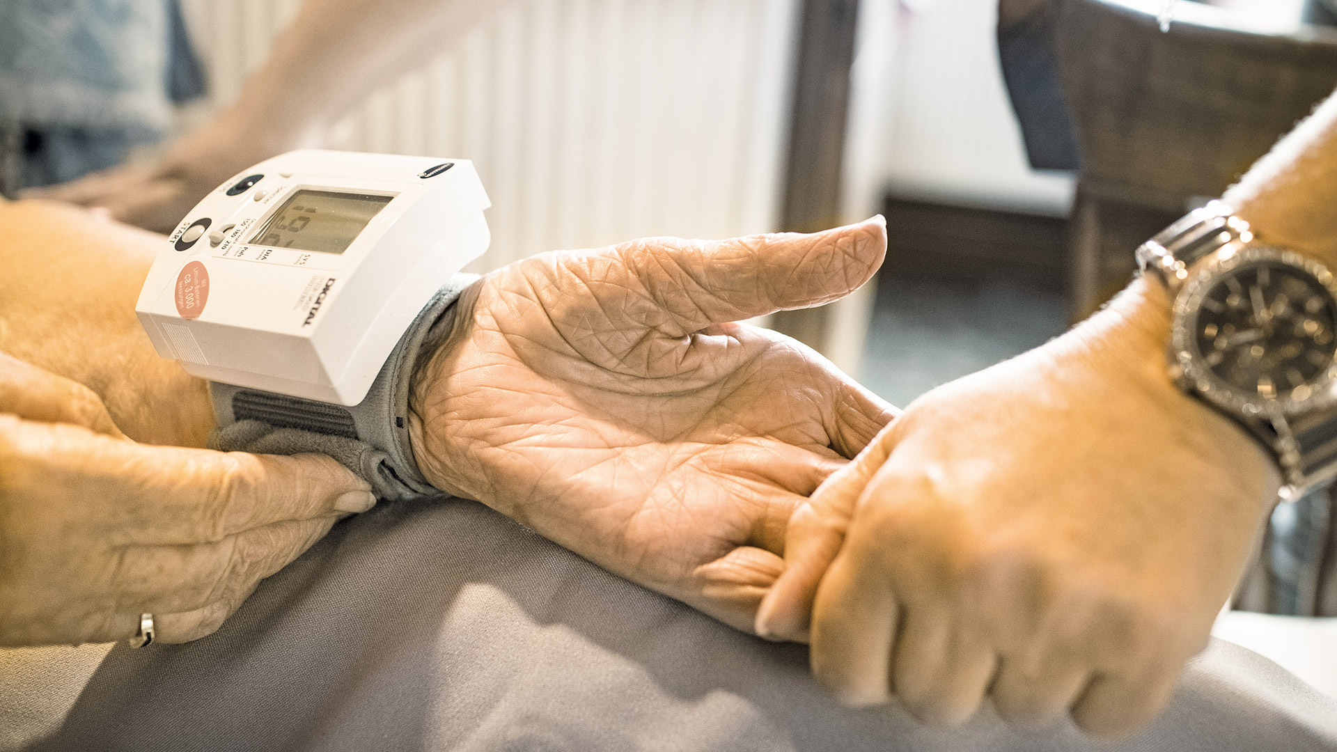 Eine ältere Hand mit Blutdruckmessgerät