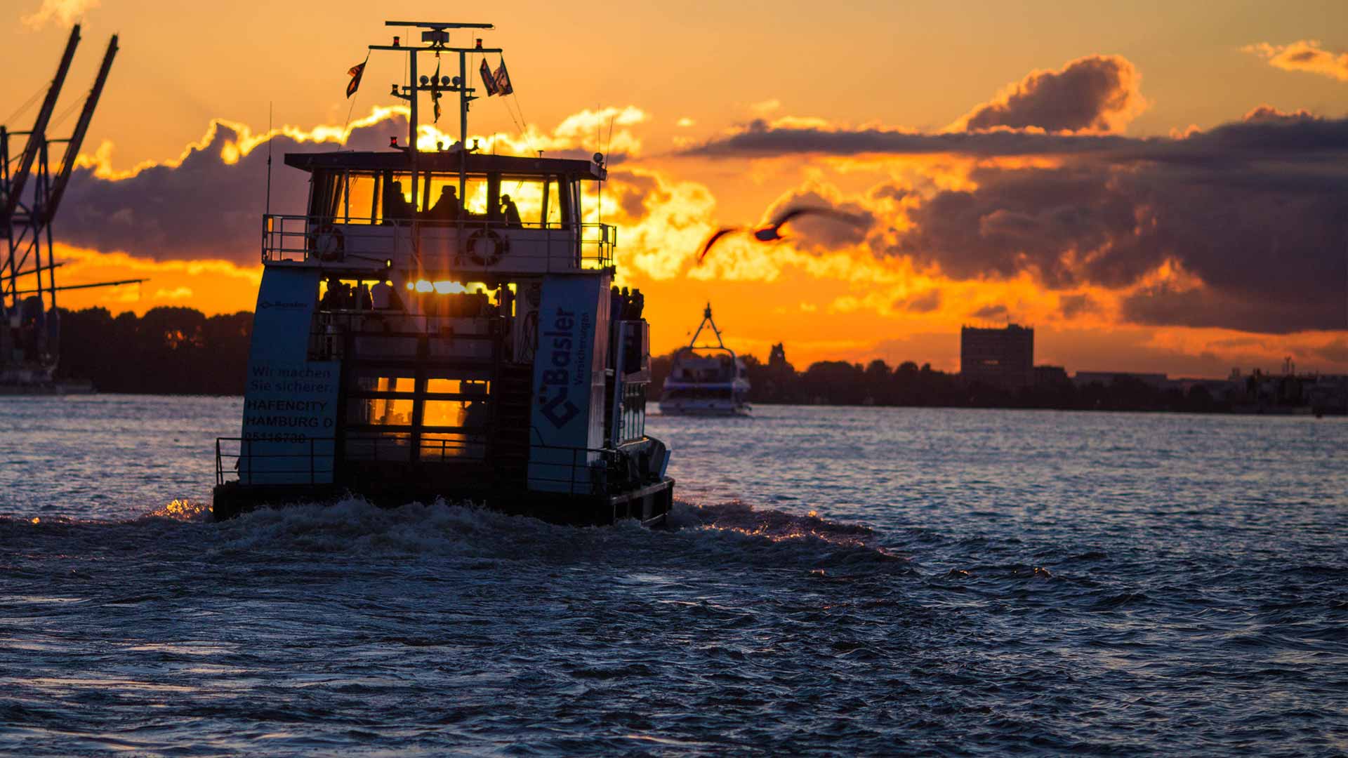 Ein Schiff fährt im Hamburger Hafen dem Sonnenuntergang entegegen