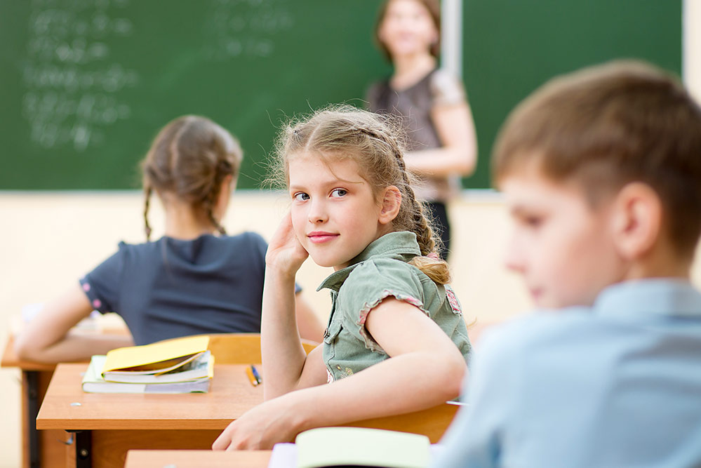 Ein Mädchen schaut in einer Klassen- und Lernsituation nach hinten.