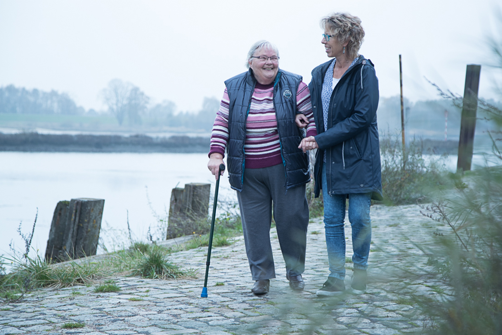 Ältere Dame und Ihre Begleitung gehen am Wasser spazieren