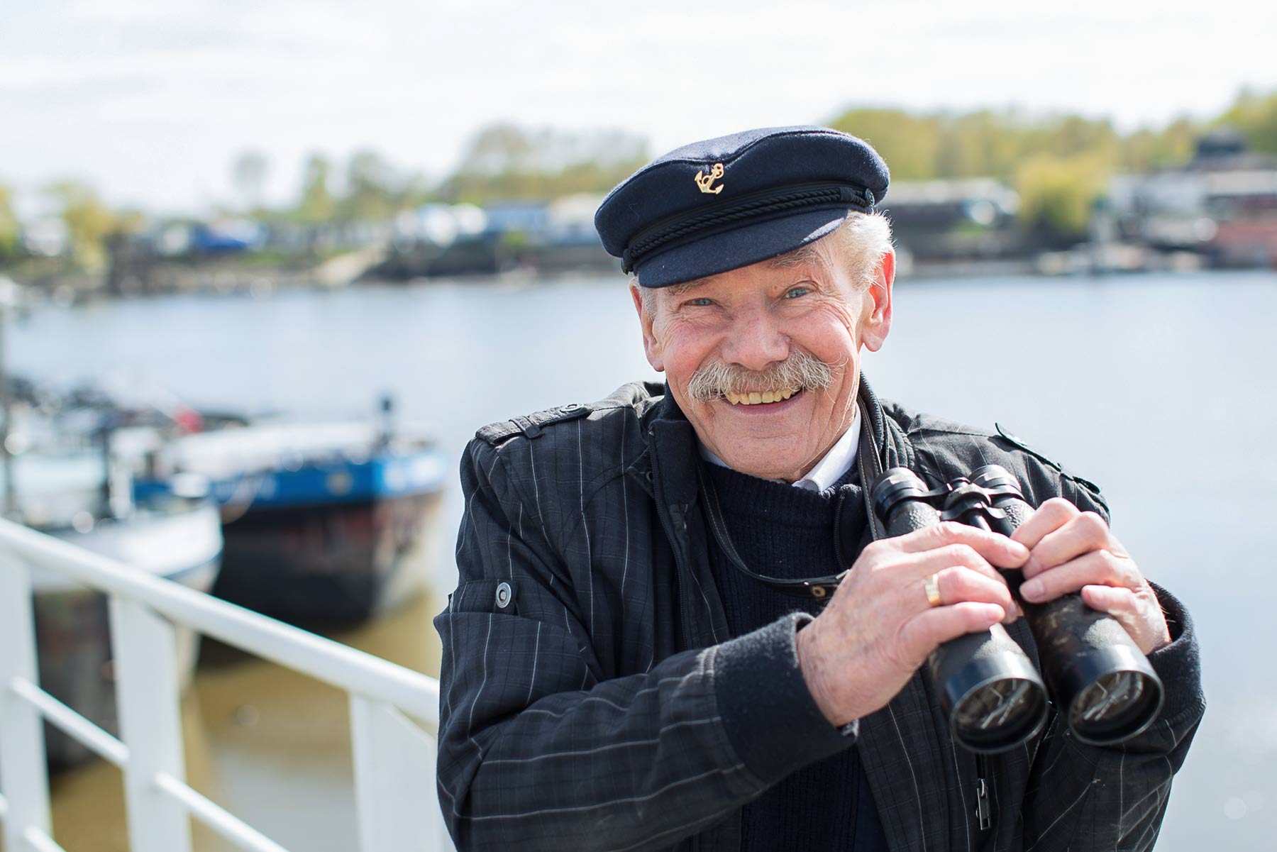 Älterer Herr hält Fernglas in der Hand und lächelt