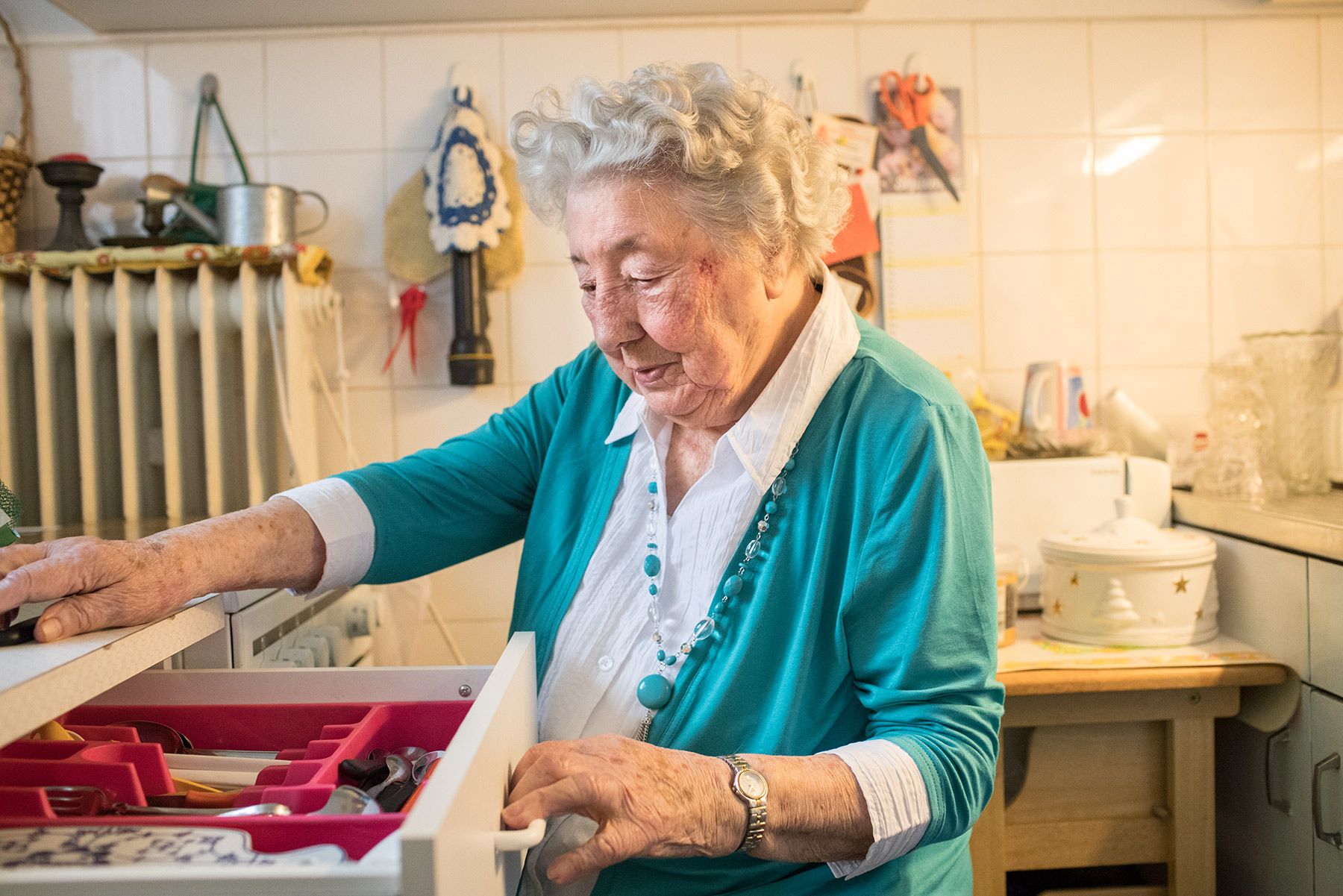 Ältere Dame schaut in eine Schublade mit Besteck