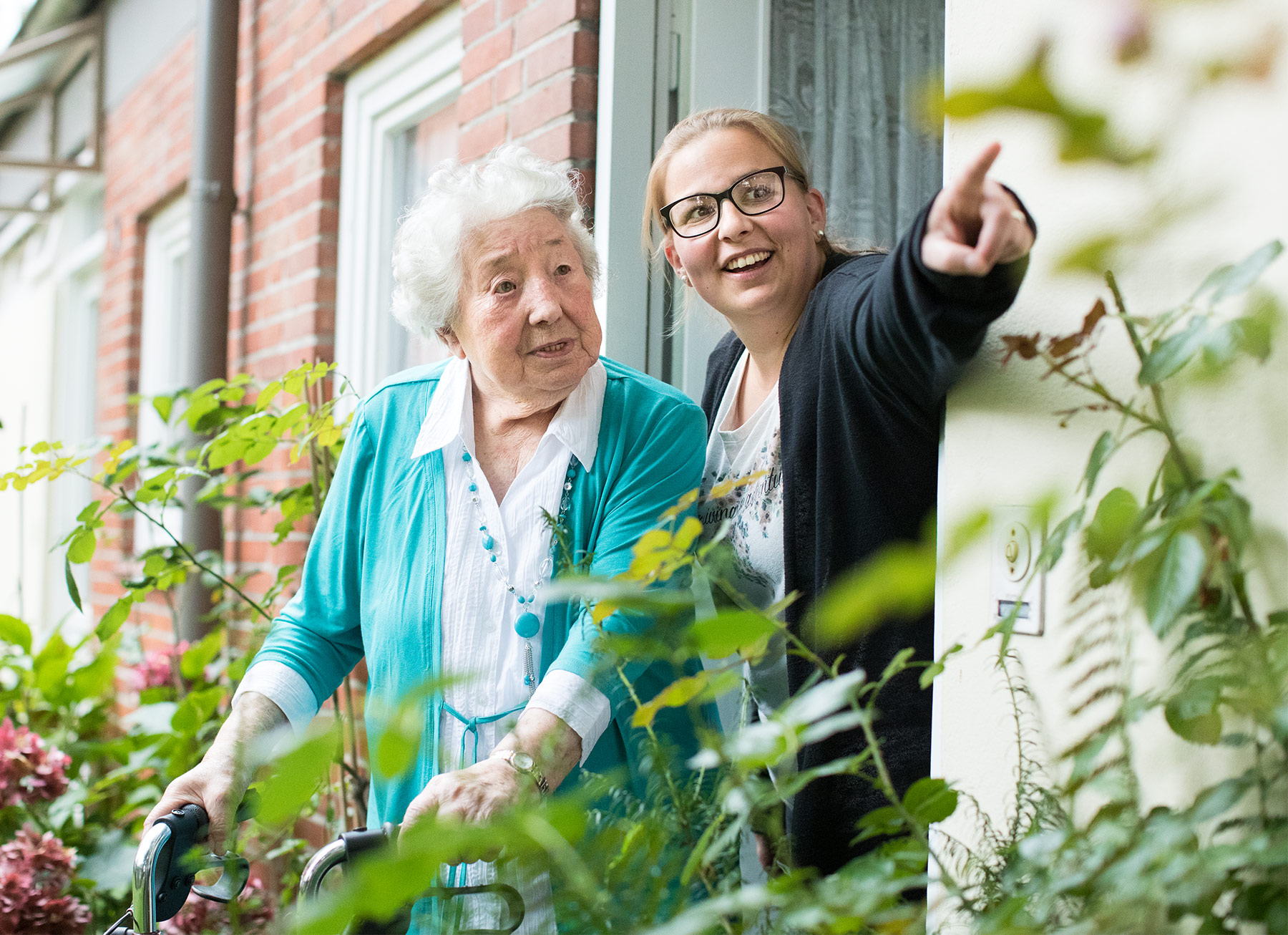 Alte Frau stützt sich auf einem Rollator in Ihrer Wohnung ab